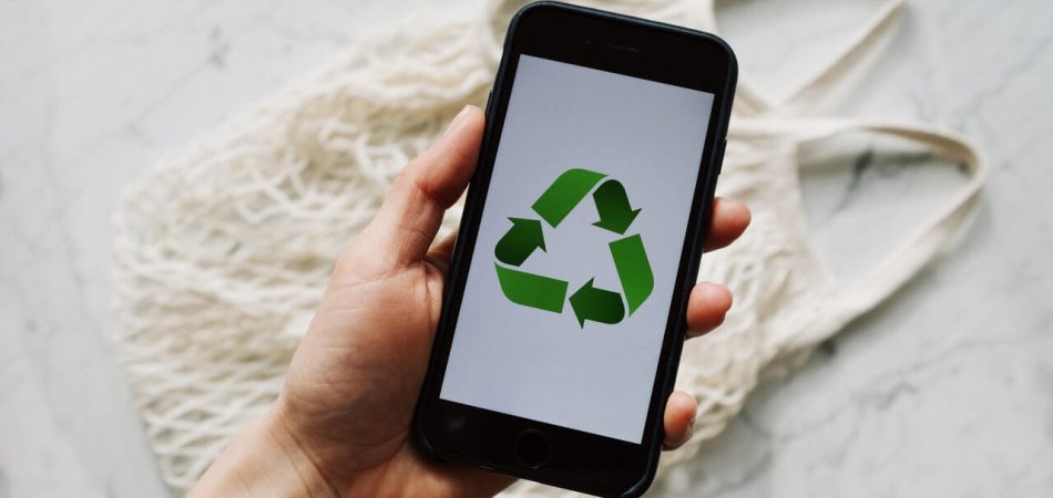 Person holding a phone showing a recycling symbol displayed on screen